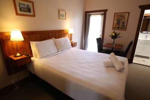 a bedroom with a large white bed with two pillows at Belgravia Mountain Guest House in Katoomba