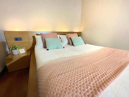 1 dormitorio con 1 cama grande con almohadas rosas y azules en Casa de la lonja, en Fondón