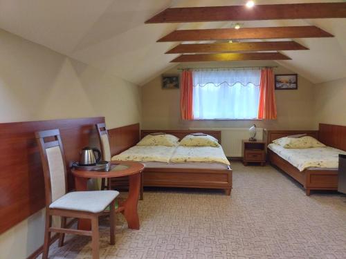 a bedroom with two beds and a table and a window at Willa Onyks in Szklarska Poręba