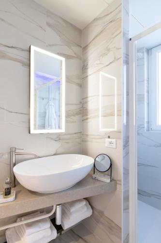 a bathroom with a white tub and a mirror at Hatelier Garda Home by Enjoy Garda Hotel in Peschiera del Garda