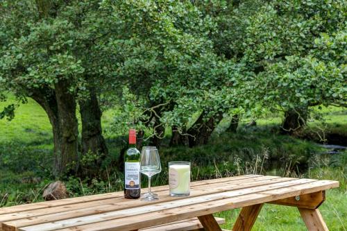 a wooden table with two bottles of wine and a glass at River Fishing I Hot tub I Games Room I PetFriendly in Rainow
