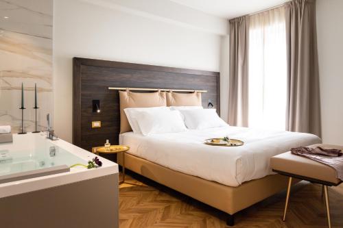 a bedroom with a large bed and a bath tub at Hatelier Garda Home by Enjoy Garda Hotel in Peschiera del Garda