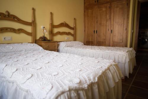two beds in a room with white bedspreads at Apartamentos Rurales Arco de Trajano in Alcántara