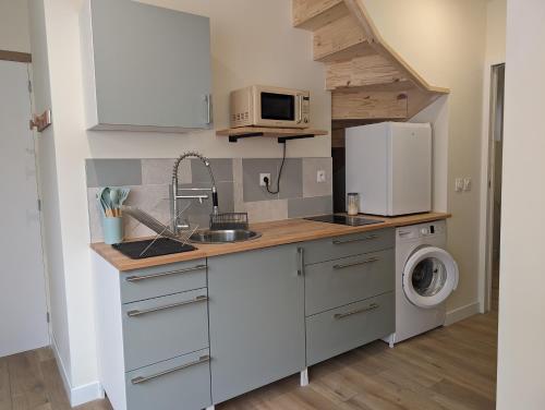 une petite cuisine avec un évier et un réfrigérateur dans l'établissement T2 à 15 minutes de Paris, à Gennevilliers