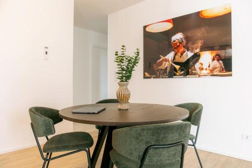 a dining room table with chairs and a vase on it at Media Bay Apartments in Kirchberg by Rentaroo in Luxembourg