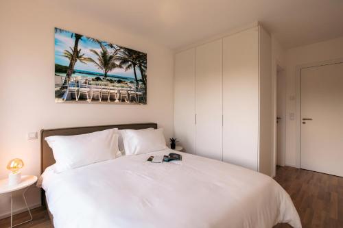 a bedroom with a white bed and a picture of the beach at Media Bay Apartments in Kirchberg by Rentaroo in Luxembourg