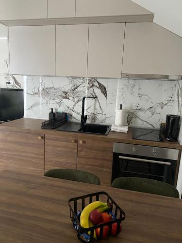 a kitchen with a basket of fruit on a table at Apartmani Lazarevic Jagodina in Jagodina