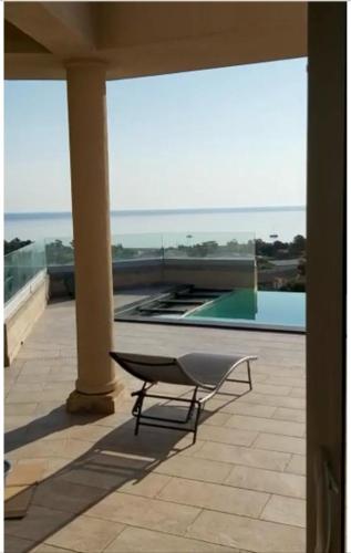 une chaise assise sur une terrasse à côté d'une piscine dans l'établissement Maison Solenzara vue mer, à Sari-Solenzara