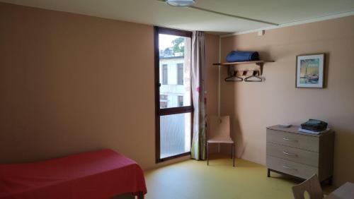 a bedroom with a bed and a window and a dresser at Maison d'accueil Franciscaine in Orsay