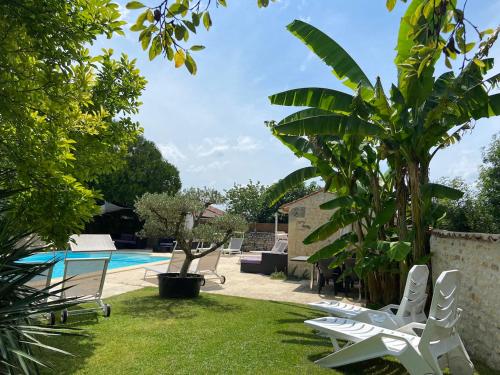 une cour avec des chaises blanches et une piscine dans l'établissement LODGE Champêtre Glamping, à Chadenac