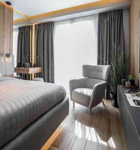 a bedroom with a bed and a chair and a window at Aristotelian Virtues - Sophia in Thessaloniki