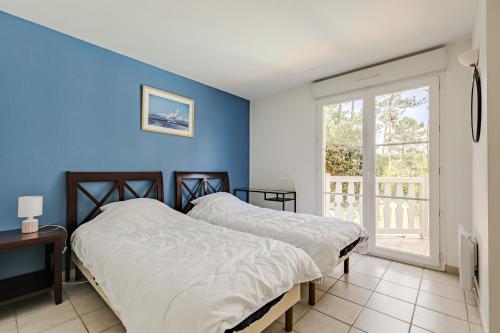 - 2 lits dans une chambre avec un mur bleu dans l'établissement villa piscine 4ch dans la pinede a 4min de l ocean AG1, à Lacanau