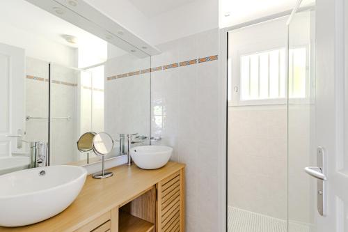une salle de bain blanche avec un lavabo et un miroir dans l'établissement villa piscine 4ch dans la pinede a 4min de l ocean AG1, à Lacanau