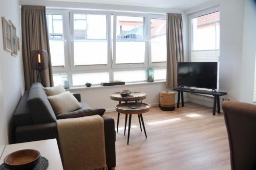 a living room with a couch and a tv at Ferienwohnungen Momentum Norderney in Norderney