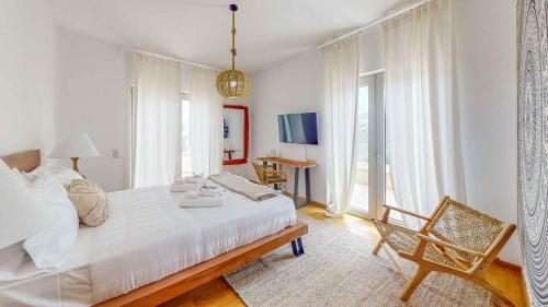 Un dormitorio blanco con una cama grande y una silla. en helidoni luxury villa, en Kokkíni Khánion