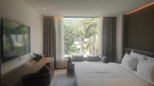 Una habitación de hotel con una cama y una ventana grande. en ZANA in the Wild Dhikuli Jim Corbett, en Garjia