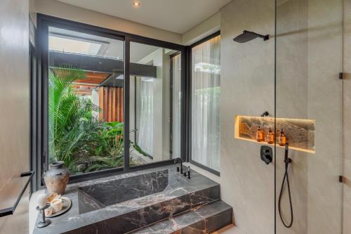 a bathroom with a large window and a shower at Villa Morada Canggu by Nakula in Dalung