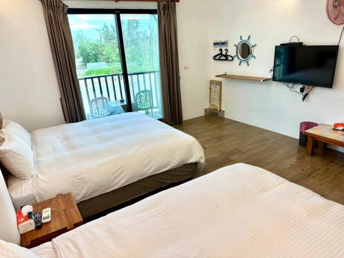 a hotel room with two beds and a flat screen tv at Nanwan254 Homestay in Nanwan
