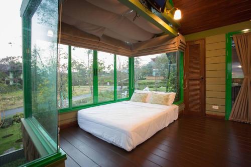 a bedroom with a bed in a room with windows at Naralin Khao Yai Mountain View Pool Villa in Pak Chong