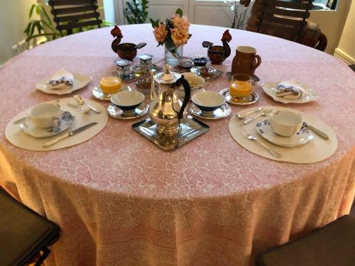 une table rose avec une nappe, des assiettes et des tasses roses dans l'établissement Les Pensées - Chambre Turner, à Orléans