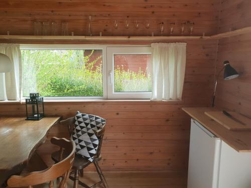 a kitchen with a table and chairs and a window at Rinkenæshus Hytte B in Gråsten