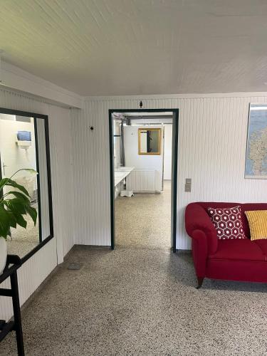 a living room with a red couch and a mirror at Rinkenæshus Hytte B in Gråsten