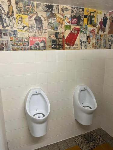 two urinals in a bathroom with posters on the wall at Rinkenæshus Hytte C in Dalsgård