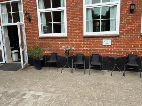 a group of chairs and tables in front of a brick building at Rinkenæshus Das kleine Zimmer in Dalsgård