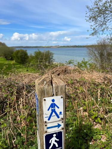 a blue and white sign on a wooden pole at Rinkenæshus Das kleine Zimmer in Dalsgård