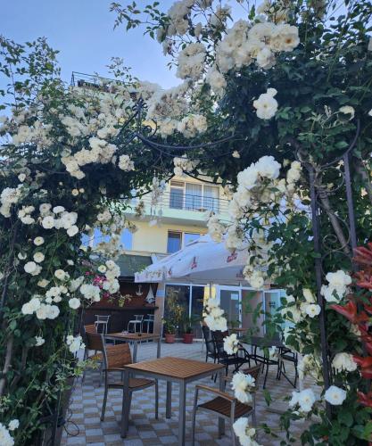 a patio with tables and chairs and white flowers at Mirana Family Hotel in Burgas City