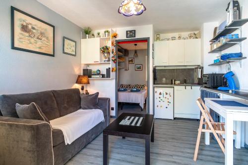 un salon avec un canapé et une table et une cuisine dans l'établissement Le Ptit Loup de Mer - Appt proche plage terrasse, à Saint-Nic