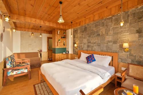 a bedroom with a large bed and a couch at Jomotel Dayaar - An Apple Orchard Villa in Theog