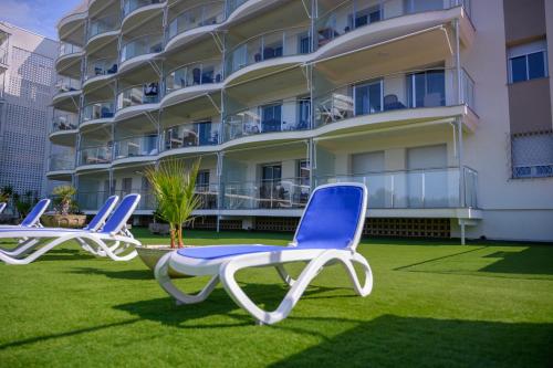 three chairs sitting on the grass in front of a building at Albatros Family in Salou