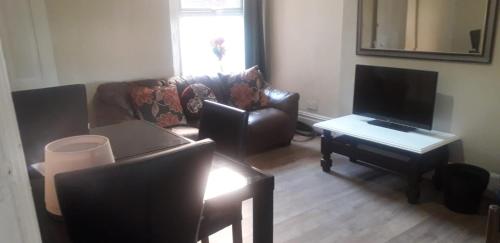 a living room with a couch and a television at Bright Home Guest House in Manchester