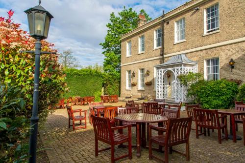 a patio with tables and chairs in front of a building at London Chigwell Prince Regent Hotel, BW Signature Collection in London