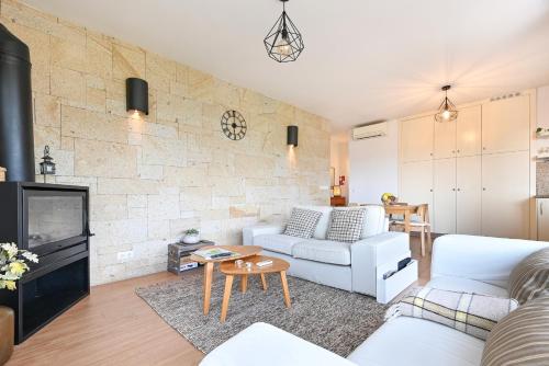 a living room with white furniture and a brick wall at Casas das Olas in Arcos de Valdevez