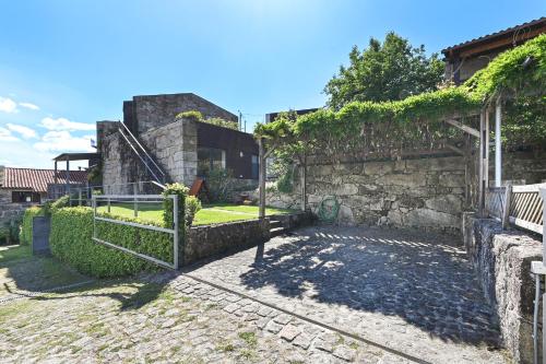 a stone wall with a gate in a yard at Casas das Olas in Arcos de Valdevez