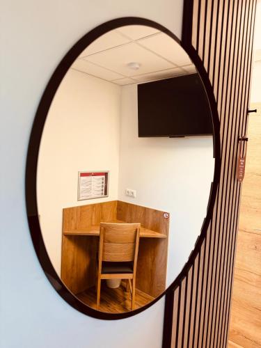 a mirror reflecting a table and a chair in a room at Enns Sleep Gasthaus Backhendlstation in Enns