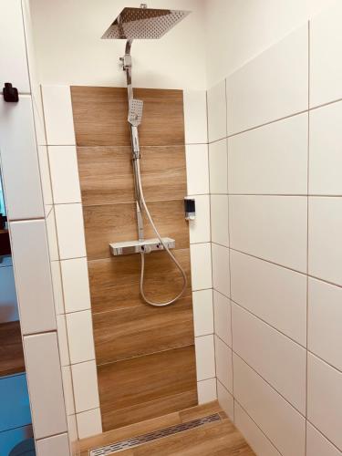 a shower in a bathroom with white tiles at Enns Sleep Gasthaus Backhendlstation in Enns
