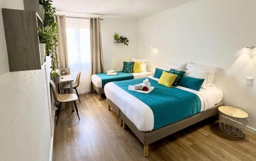 a hotel room with two beds and a table at Hotel L'Escapade in Le Lavandou
