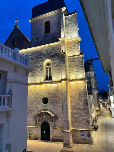 Une ancienne église avec une tour avec une horloge. dans l'établissement Charmant studio en hyper centre, à Les Sables-dʼOlonne