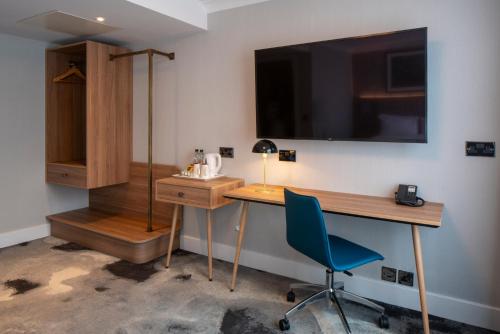 a room with a desk and a television on a wall at London Chigwell Prince Regent Hotel, BW Signature Collection in London