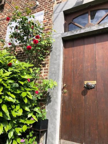 a wooden door with roses on a brick building at Le petit chapitre in Fosses-La-Ville