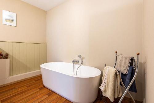 a white bath tub in a bathroom with wooden floors at Le petit chapitre in Fosses-La-Ville