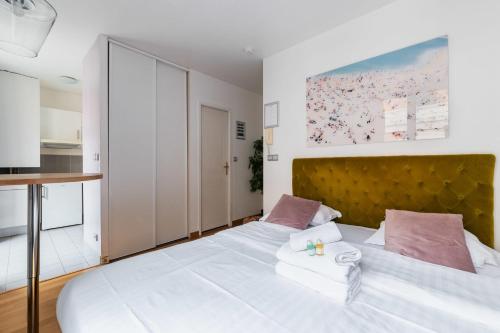 une chambre avec un grand lit blanc avec des oreillers roses dans l'établissement 204 - Charmant studio jardins des plantes -Paris 5 - FLAT-GUEST, à Paris