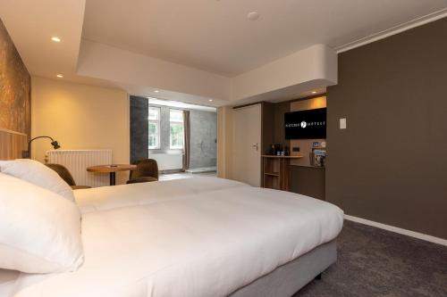a bedroom with a large white bed and a kitchen at Fletcher Hotel Restaurant Erica in Berg en Dal