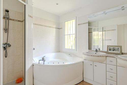 La salle de bains est pourvue d'une baignoire, de 2 lavabos et d'une douche. dans l'établissement Villa familiale avec piscine dans la pinède à 4min de l'océan-AG13, à Lacanau