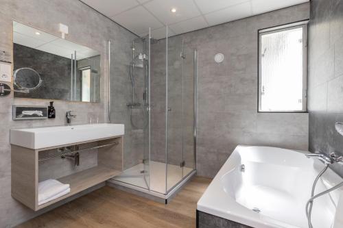 a bathroom with a sink and a glass shower at Fletcher Hotel Restaurant Erica in Berg en Dal