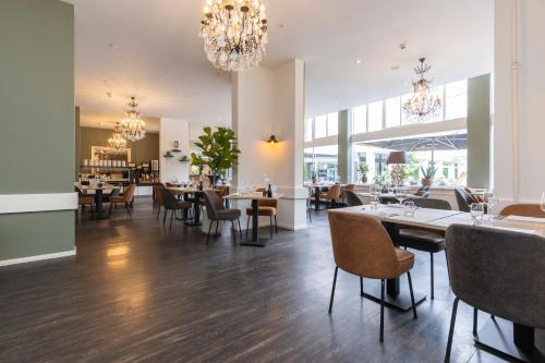 a dining room with tables and chairs and chandeliers at Fletcher Hotel Restaurant Erica in Berg en Dal