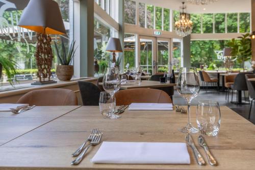 a table in a restaurant with glasses and napkins at Fletcher Hotel Restaurant Erica in Berg en Dal